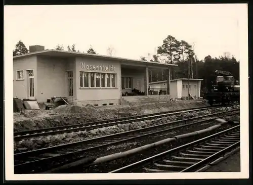 Fotografie unbekannter Fotograf, Ansicht Nassenheide, Güterzug mit Kran-LKW passiert den Bahnhof