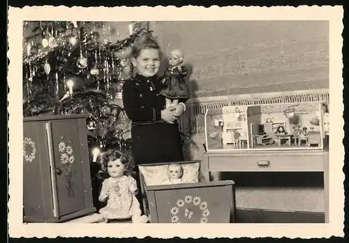 Fotografie Weihnachten, Mädchen mit Puppe & Puppenstube neben dem Weihnachtsbaum