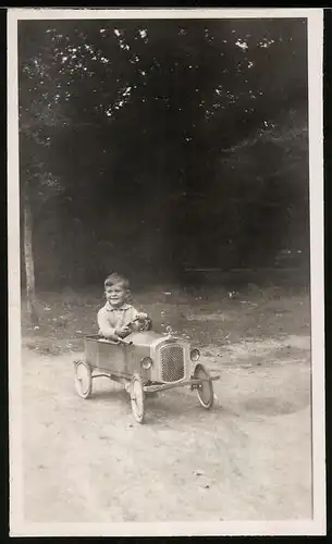 Fotografie Knabe in Tretauto - Seifenkiste sitzend, Spielzeug-Auto