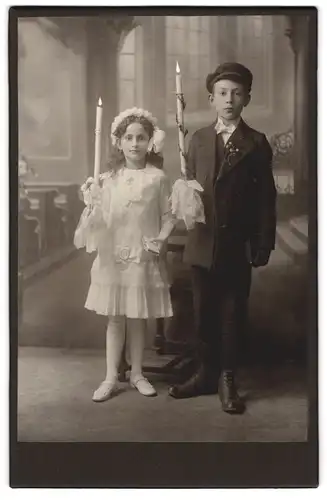 Fotografie unbekannter Fotograf und Ort, Portrait zwei niedliche Kinder zu ihrer Kommunion im Kleid und Anzug mit Kerze