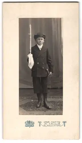 Fotografie Gebr. Martin, Augsburg, Portrait kleiner Knabe im Anzug mit Hochwasserhosen zu seiner Kommunion, 1918