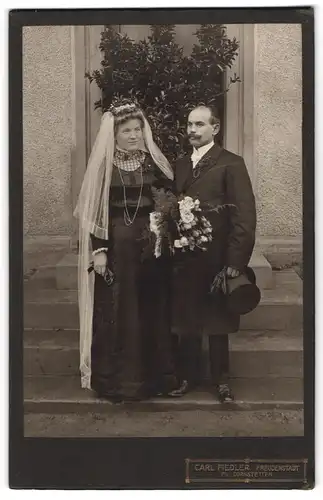 Fotografie Carl Fiedler, Freudenstadt, Brautpaar ims chwarzen Hochzeitskleid und Anzug mit Zylinder und Brautstrauss