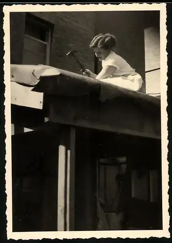 Fotografie Dachdeckerin, junge Frau nagelt neue Dachpappe auf ein Vordach 1953