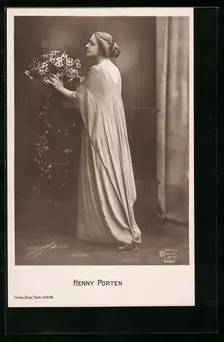 AK Schauspielerin Henny Porten im langen Gewand neben einer Blumenvase