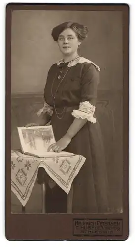 Fotografie Heinrich Petersen, Schleswig, Junge Dame im Kleid mit einem Buch