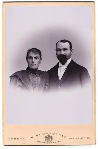 Fotografie H. Schwegerle, Lübeck, Breite-Strasse 31, Junge Frau mit Kreuzkette und junger Mann mit Bart und Schnauzer