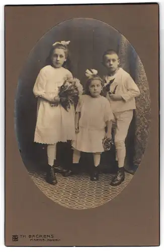 Fotografie Th. Backens, Marne /Holstein, Zwei Mädchen mit Blumen und Junge mit Pfeife im Matrosenanzug