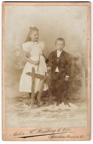 Fotografie H. Herzberg & Co., Spandau, Breitestrasse 35, Lächelndes Mädchen im weissen Kleid und Junge im Anzug