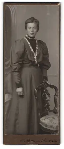 Fotografie F. Mürnseer, Karlsruhe, Rüppurerstrasse 16, Junge Dame in dunklem Kleid an Stuhl stehend