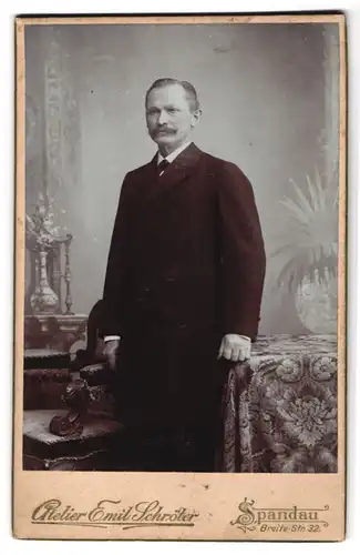 Fotografie Atelier Emil Schröter, Berlin-Spandau, Breitestrasse 32, Gestandener Mann im Anzug mit Mantel