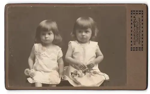 Fotografie Heinrich Wolf, Perchtoldsdorf, Hochstr. 1, Zwei kleine Mädchen in Kleidern mit Blumen