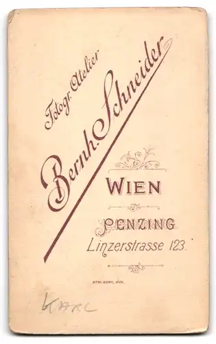 Fotografie Bernh. Schneider, Wien-Penzing, Linzerstr. 123, Süsses Kleinkind im Kleid mit Rassel liegt auf Fell