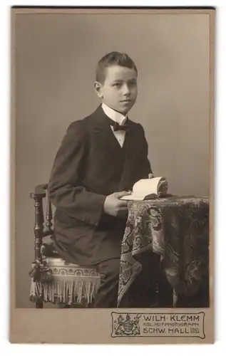 Fotografie Wilh. Klemm, Schw. Hall, Junger Mann im Anzug mit einem Buch