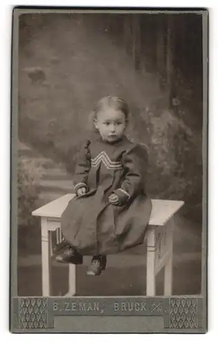 Fotografie B. Zeman, Bruck a. Mur, Wienergasse 11-13, Kleines Mädchen mit baumelnden Beinen auf einem Tisch