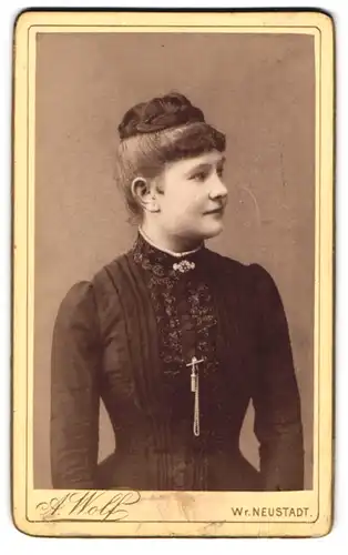 Fotografie A. Wolf, Wr. Neustadt, Baumkirchnerring 11, Lächelnde junge Frau mit zeitgenössischer Frisur und Brosche
