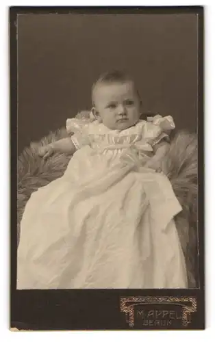Fotografie M. Appel, Berlin-NO, Neue Königstr. 1, Süsses Kleinkind im Kleid sitzt auf Fell