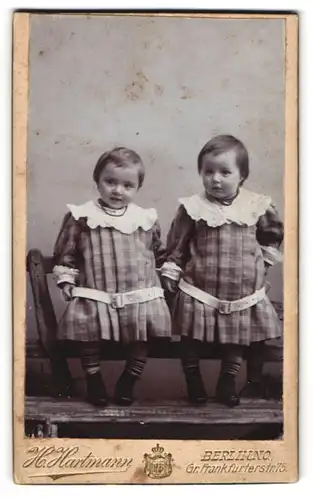 Fotografie H. Hartmann, Berlin-NO, Gr. Frankfurterstr. 75, Zwei kleine Mädchen in karierten Kleidern