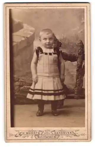 Fotografie H. Boodts, Hannover, Schillerstrasse 52, Kleines Kind mit kurzen Haaren im Kleidchen