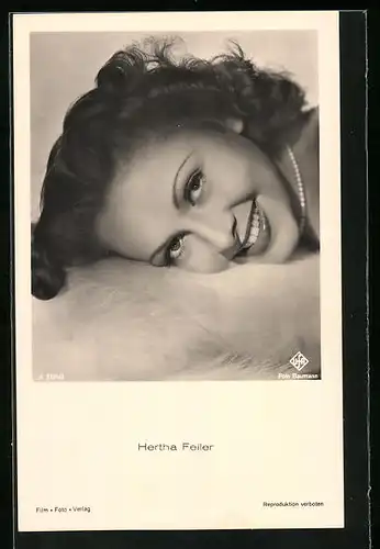 AK Schauspielerin Hertha Feiler mit dem Kopf auf einem Fell in die Kamera lächelnd