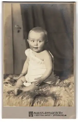 Fotografie Augsut Rathgeber, Oppenheim a. Rh., Süsses Kleinkind im Hemd sitzt auf Fell