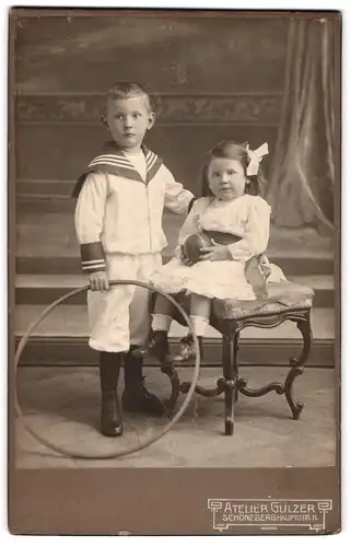 Fotografie Atelier Gülzer, Schöneberg, Hauptstrasse 11, Junge mit Spielreif und Mädchen mit Haarschleife und Ball