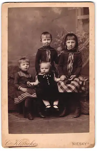 Fotografie C. Klaucke, Niesky o. L., Drei entspannt blickende Kinder mit Baby im Samtkleid in ihrer Mitte
