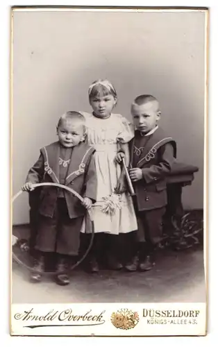 Fotografie Arnold Overbeck, Düsseldorf, Königs-Allée 43, Mädchen im Kleid und zwei Jungen mit Reifen