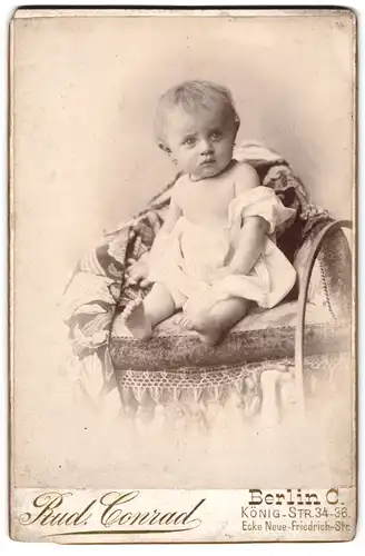 Fotografie Rud. Conrad, Berlin O., Königstrasse 34-36, Kleinkind in weissem Tuch auf Sessel