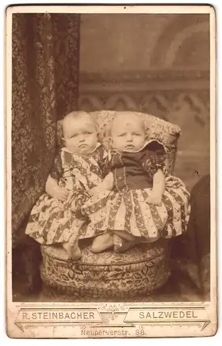 Fotografie R. Steinbacher, Salzwedel, Neuperverstrasse 38, Zwei Babys in Kleidchen auf einem Sitzmöbel