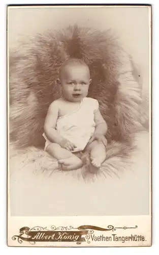 Fotografie Albert König, Vaethen-Tangerhütte, Süsses Kleinkind im Hemd sitzt auf Fell