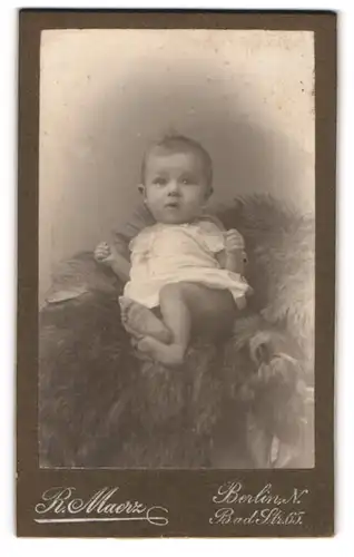 Fotografie R. Maerz, Berlin, Bad-Str. 65, Portrait süsses Baby im Hemdchen auf Fell liegend