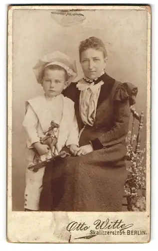Fotografie Otto Witte, Berlin, Skalitzerstr. 54, Portrait stolze Mutter mit frechem Buben und Spielzeugpferd