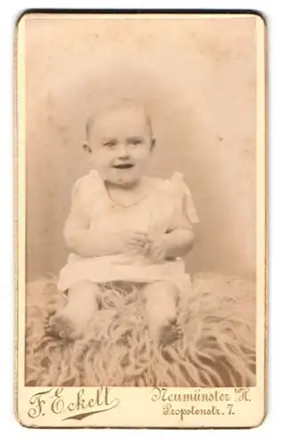 Fotografie F. Eckell, Neumünster i. H., Probstenstr. 7, Portrait lachendes süsses Baby im weissen Kleidchen