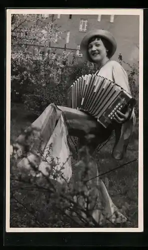 AK Junge Frau sitzt im Garten und spielt ihr Akkordeon