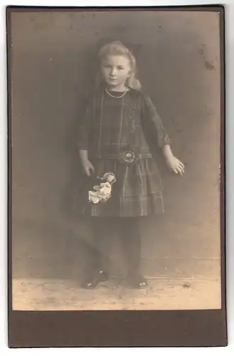 Fotografie unbekannter Fotograf und Ort, Kleines Mädchen in kariertem Kleid hält Blumen