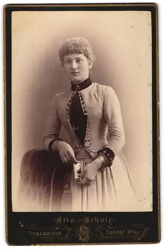 Fotografie Otto Schulz, Osnabrück, Domhof 4a., Junge Dame mit gelocktem Haar hält ein Foto in den Händen