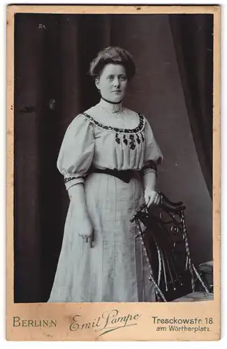 Fotografie Emil Lampe, Berlin, Treschkowstr. 18, Dame mit toupierten Haaren steht hinter Stuhl