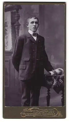 Fotografie M. Scheinfuss, Reichenbach i. V., Bahnhofstr. 9, Bursche im Anzug durchblättert Katalog
