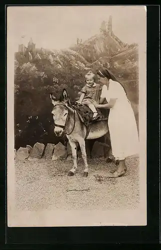Foto-AK Kleinkind beim Eselreiten vor Kulisse