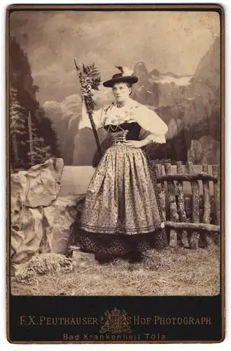 Fotografie F. X. Peuthauser, Bad Tölz, Portrait junge Frau im Trachtenkleid mit Wanderstock vor einer Alpenkulisse