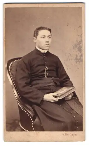 Fotografie G. Haslinger, St. Pölten, Portrait junger Pfarrer im Talar mit Fotoalbum in der Hand