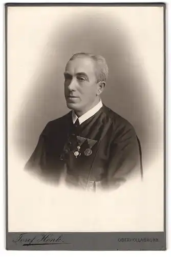 Fotografie Josef Henk, Oberhollabrunn, Portrait Pfarrer Raphale im Genwad mit Orden an der Brust, 1909