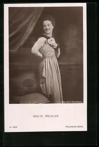 AK Schauspielerin Dorrit Weixler steht lächelnd neben einem Stuhl