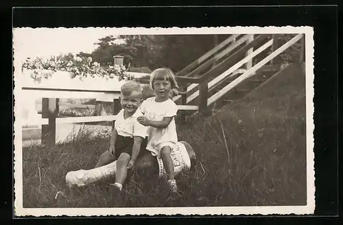 Foto-AK Süsses Kinderpaar sitzt auf einer grossen Sektflasche