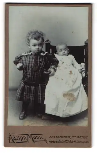 Fotografie Adolph Mann, Hamburg, Reeperbahn 103, Kleines Kind mit Lockenkopf und Baby im Taufkleidchen