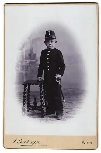 Fotografie F. Gertinger, Wien, Portrait junger Knabe als K.u.K. Kadett in Uniform mit Tschako udn Säbel