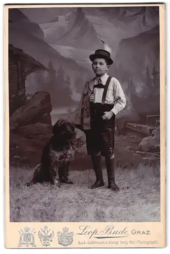 Fotografie Leop. Bude, Graz, Portrait junger Knabe in Lederhosen mit seinem Hund im Atelier