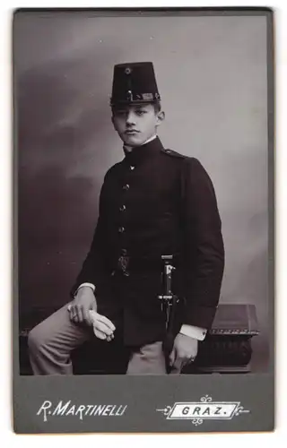 Fotografie R. Martinelli, Graz, junger Knabe als K.u.K. Kadett in Uniform mit Bajonett und Portepee