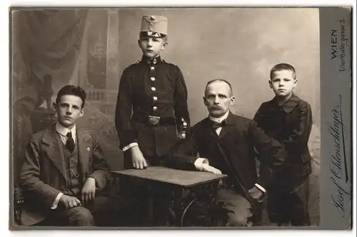 Fotografie Josef Ohlenschlager, Wien, Portrait Vater mit seinen Söhne, Knabe als K.u.K. Kadett in Musiker Uniform