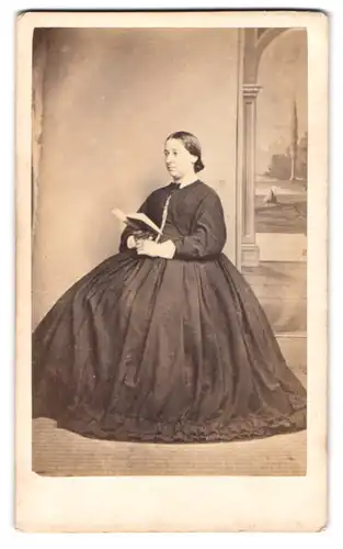 Fotografie J. Mitchell, Truro, Pyder Street, Jungee Dame mit zusammen gebundenem Haar imd Reifrockkleid ein Buch lesend